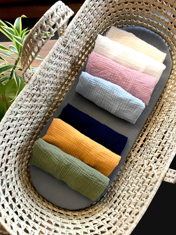 Custom size and shape fitted sheet for Moses basket, bassinet, cradle, crib. Sheet is shown rolled up with 7 different colors. Fitted sheets come in a variety of patterns and fabrics, including cotton, organic cotton, linen, minky dot and cotton prints.