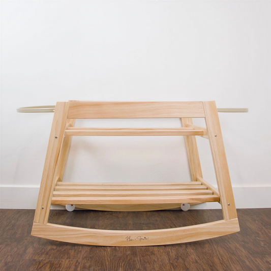 A wooden rocking chair with a curved backrest and footrests, positioned on a wooden floor against a white wall.