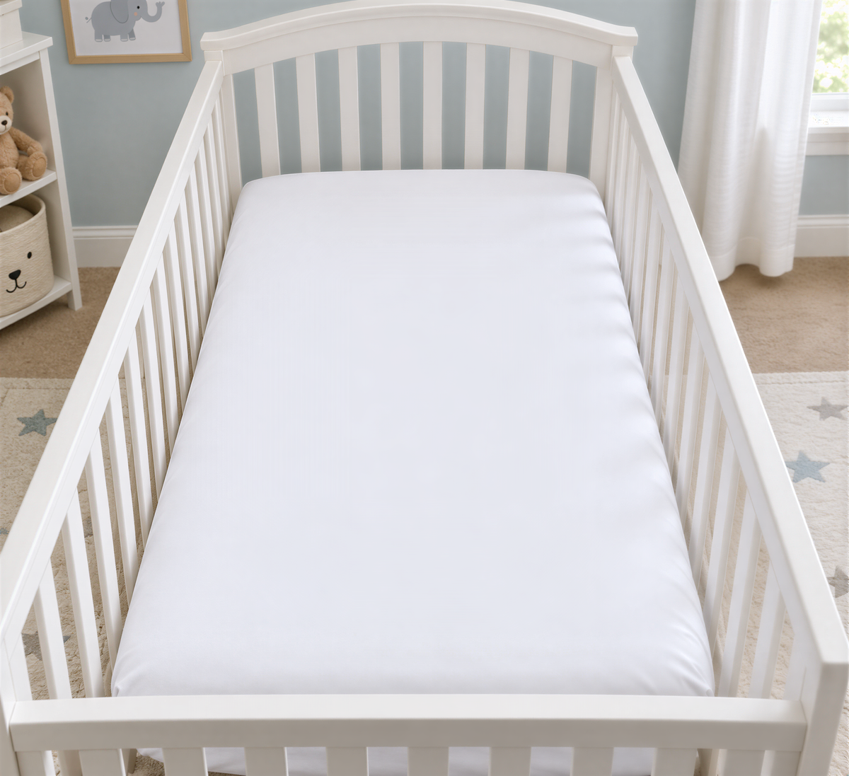 A white crib with a white mattress in a nursery room.