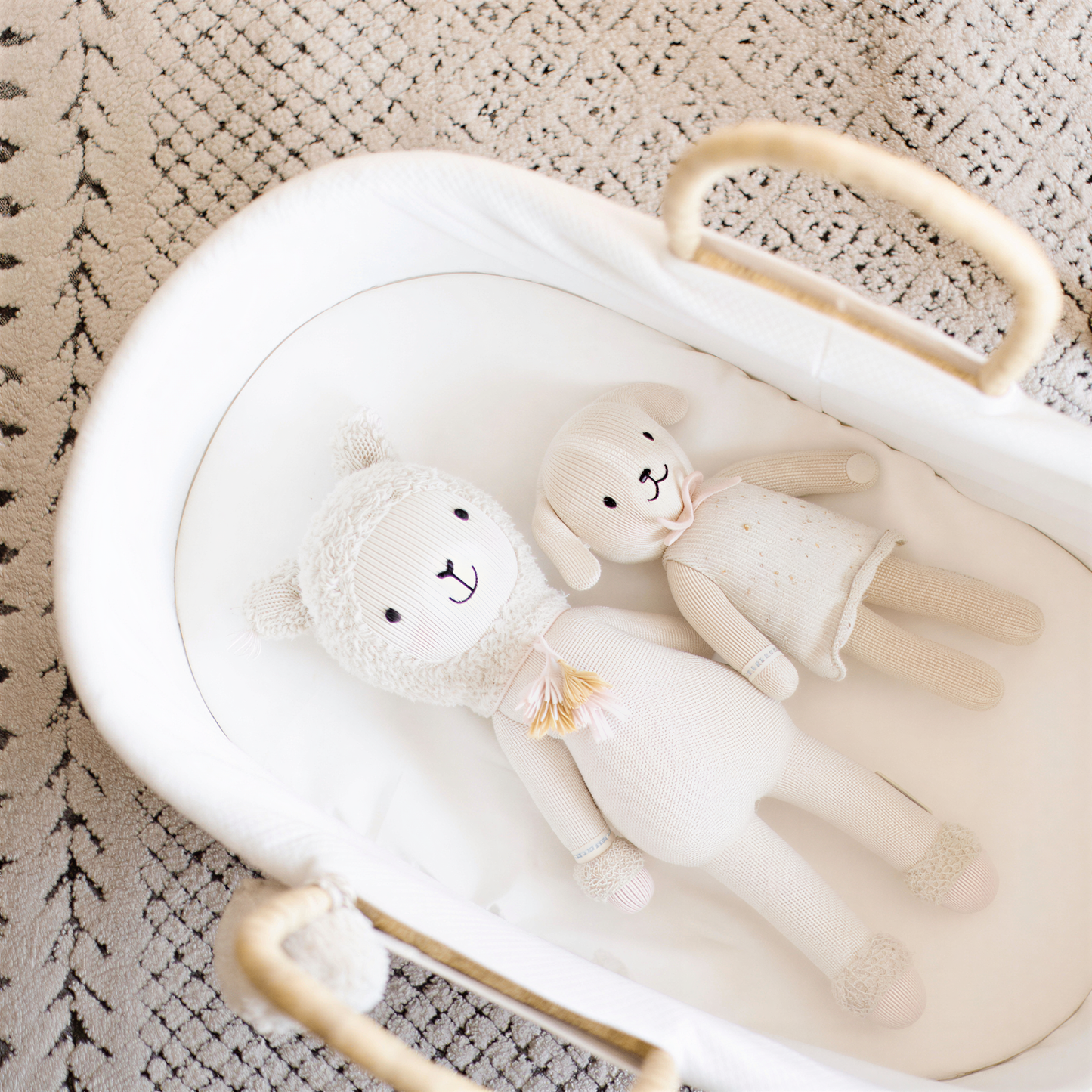 Two white stuffed animals, a dog and a lamb, are lying in a white basket with a woven handle.