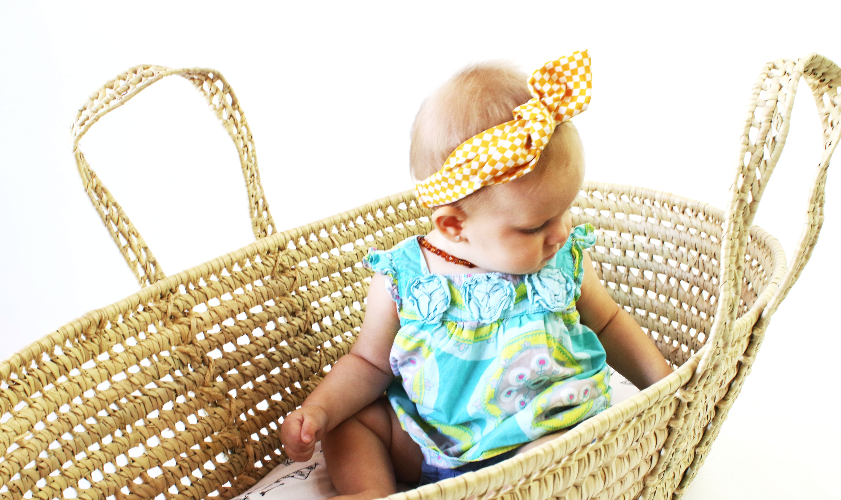 baby girl in palm leaf moses basket looking over her shoulder comfortable and cozy ready to sleep, nap, play or rest