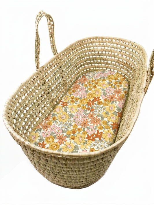 A woven basket with a floral patterned mattress inside.